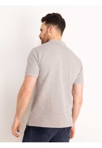 Grijze polo met korte mouwen, klassieke kraag, ontspannen pasvorm, zijsplitten, gemaakt van een zachte katoenmix, eenvoudige ontwerp zonder patronen.