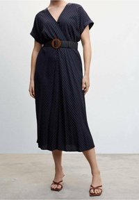 Mustapukuinen kietaisumekko, jossa on lyhyet ja leveät hihat. Mekossa on valkoisia pystysuoria raidoituksia ja siinä on tekstuuroitu musta vyö, jossa on ruskea pyöreä solki.