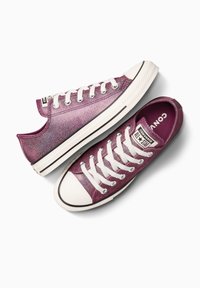 Sneakers di tela viola glitterati con lacci bianchi, design low-top e suola in gomma. Presentano una striscia nera e un logo impresso sulla linguetta.