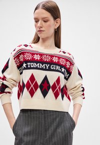 Krémszínű, kötött pulóver, piros és navy geometrikus mintákkal, bordázott nyakkivágással és mandzsettákkal, "TOMMY GIRL" felirattal a mellkasán.