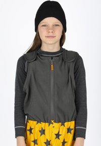 Grijze fleece vest met een ritssluiting en schouderaccenten, gedragen over een donker langemouwen shirt, gecombineerd met gele broeken met sterpatroon.