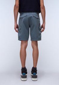 Gray cargo shorts with two side pockets and two back pockets, made from lightweight fabric. Worn with high-top sneakers and textured socks.