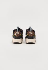 Nike Air tenisky s čierno-hnedým dizajnom, s textúrovaným zadným dielom, gumovou podrážkou, modrými akcentmi a značkovaním na päte.