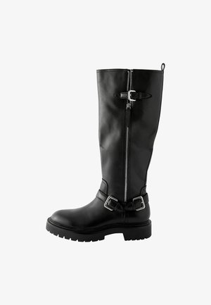 Schwarze Lederstiefel bis zum Knie mit runder Zehenpartie, seitlichem Reißverschluss und zwei Schnallenakzenten am Knöchel. Dicke, profilierte Gummisohle.