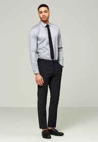 Grårandig skjorta, svart slips, svarta slim-fit byxor, eleganta svarta skor. Slät tyg med strukturerad design och skräddarsydd passform.