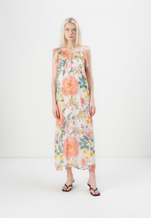 Robe maxi florale en tissu transparent avec des fleurs roses pâles, oranges et vertes ; dotée d'un encolure élastique et de bretelles réglables. Sandales noires.