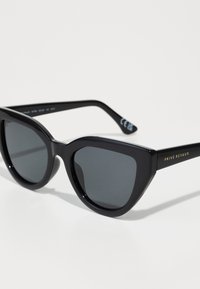 Óculos de sol pretos com um formato ousado de gato, armações de plástico lisas e lentes escuras. Apresenta uma marcação em dourado na haste.