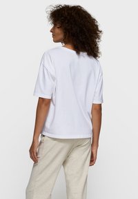 Hvid bomuld T-shirt med afslappet pasform og korte ærmer, der har en rund halsudskæring og en lige nederkant. Tekstureret, afslappet udseende.