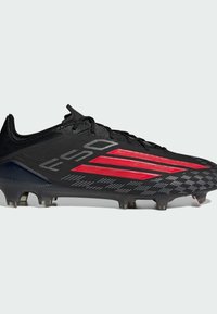 Μαύρο ποδοσφαιρικό παπούτσι με κόκκινες λεπτομέρειες και υφασμένο σχέδιο. Διαθέτει αεροδυναμικό σχήμα, συνθετικό επάνω μέρος και διαμορφωμένες πέλματα για πρόσφυση.