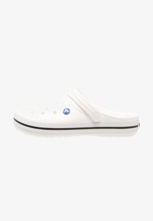 Sabot blanc à enfiler avec des trous de ventilation, bride de talon réglable et bande noire le long de la semelle.