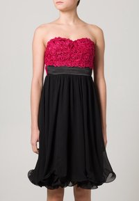 Stövelfri klänning med en fuchsia blommig spetsliv och svart flödande kjol, med en figurnära midja och volangkant.