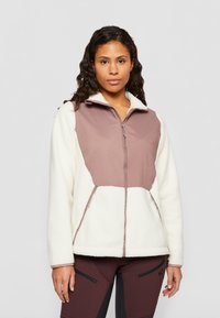 Veste en polaire avec un corps crème et un panneau avant zippé marron. Tissu texturé avec des poches latérales et un col montant.