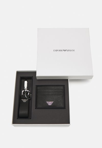 Set di portachiavi e portafoglio in pelle nera, confezionato in una scatola bianca. Il portafoglio è dotato di scomparti per carte e di un accento in logo argento. Il portachiavi presenta una chiusura metallica.