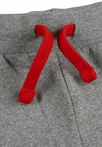 Gray sweatpants with a textured fabric. Features red drawstring and a waistband, showing thread details and stitching along the seams.
