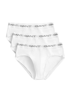 Tres calzoncillos blancos de hombre con cinturillas elásticas con el nombre de la marca "GANT" en letras negras.
