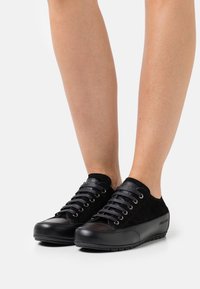 Svarta sneakers i mocka och syntetmaterial, med rundade tår, sex öglor och en texturerad sula med en logodetalj på sidan.