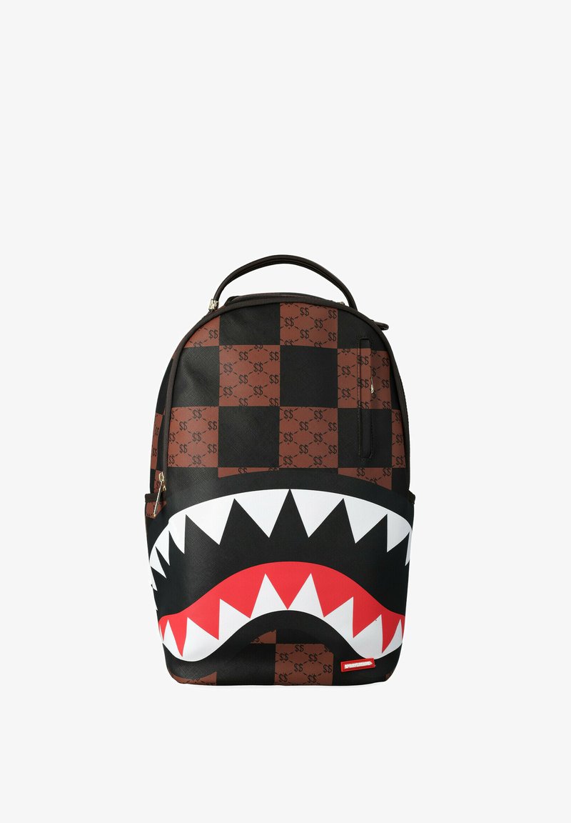 Mochila con patrón de tablero de cuadros marrón y negro con signos de dólar repetidos y una gran boca de tiburón estilizada con dientes afilados blancos y rojos.