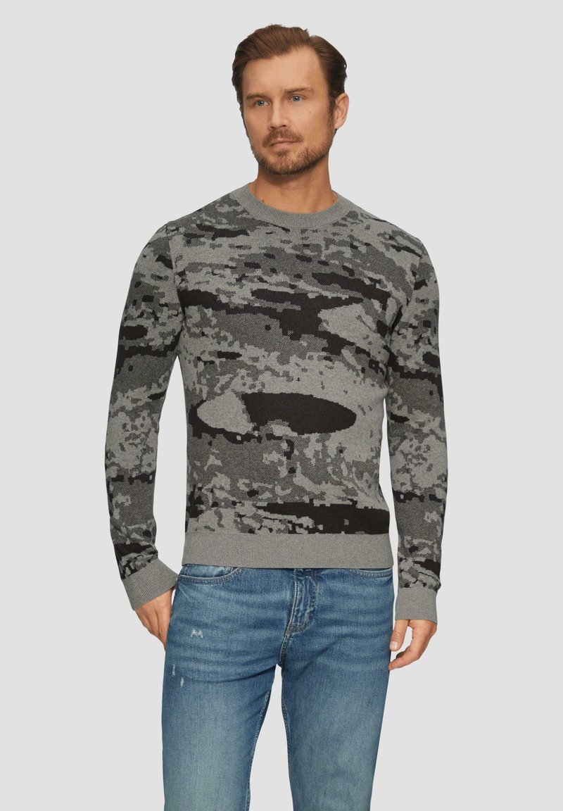 Pull en camouflage gris avec un col rond, des poignets et un ourlet côtelés. Fabriqué en tissu tricoté doux ; présente des motifs noirs et gris foncé.