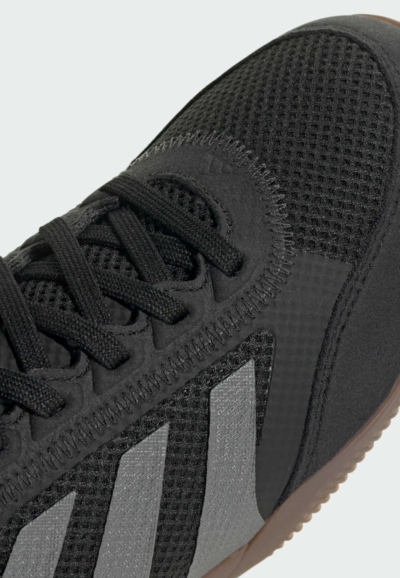 Schwarzer Sportschuh mit Oberschuh aus Mesh, strukturierten schwarzen Details und drei grauen Streifen. Verfügt über flache Schnürsenkel und eine Laufsohle aus Gummigummi.