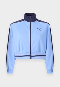 Ανοιχτό μπλε κοντό αθλητικό μπουφάν με σκούρο μπλε γιακά, ρίγες στους ώμους, ρίγες στη ζώνη, φερμουάρ μπροστά και λογότυπο Puma στο στήθος.