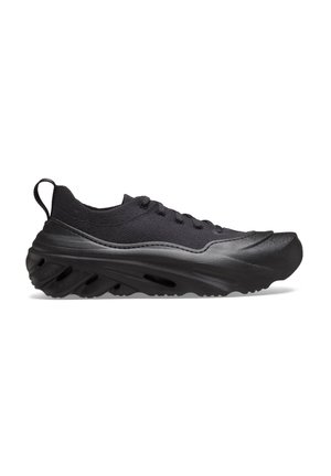 Baskets basses noires avec tige en maille, semelle épaisse texturée avec aérations et lacets à l'avant, vues de côté sur fond blanc.
