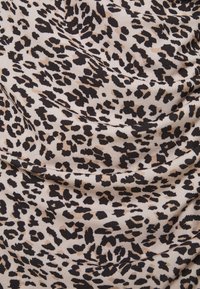 Tierdruckstoff mit einem unregelmäßigen schwarzen Leopardenmuster auf einem sandfarbenen Hintergrund, mit weichem Fall und glatter Textur.