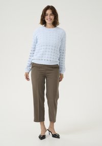 Ljusk blå texturerad stickad tröja med rund hals, kombinerad med bruna cropped byxor och svarta högklackade mule-skor.