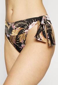 Parte de baixo de bikini em tecido preto com estampado floral tropical. Apresenta laços laterais e um detalhe em recorte para um ajuste moderno. Textura suave.
