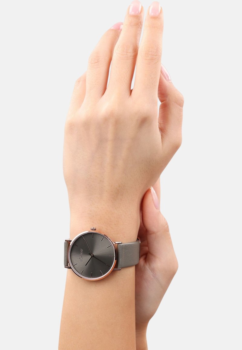 Runde Uhr mit einem dunkelgrauen mattierten Zifferblatt, silberfarbenen Stundenmarkierungen und einem grauen Lederarmband. Einfaches Design mit minimalen Hardwareakzenten.
