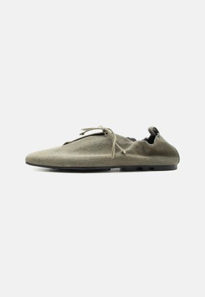 Scarpa in tessuto morbido verde oliva chiaro con suola sottile e lacci, mostrata di profilo su sfondo bianco semplice.