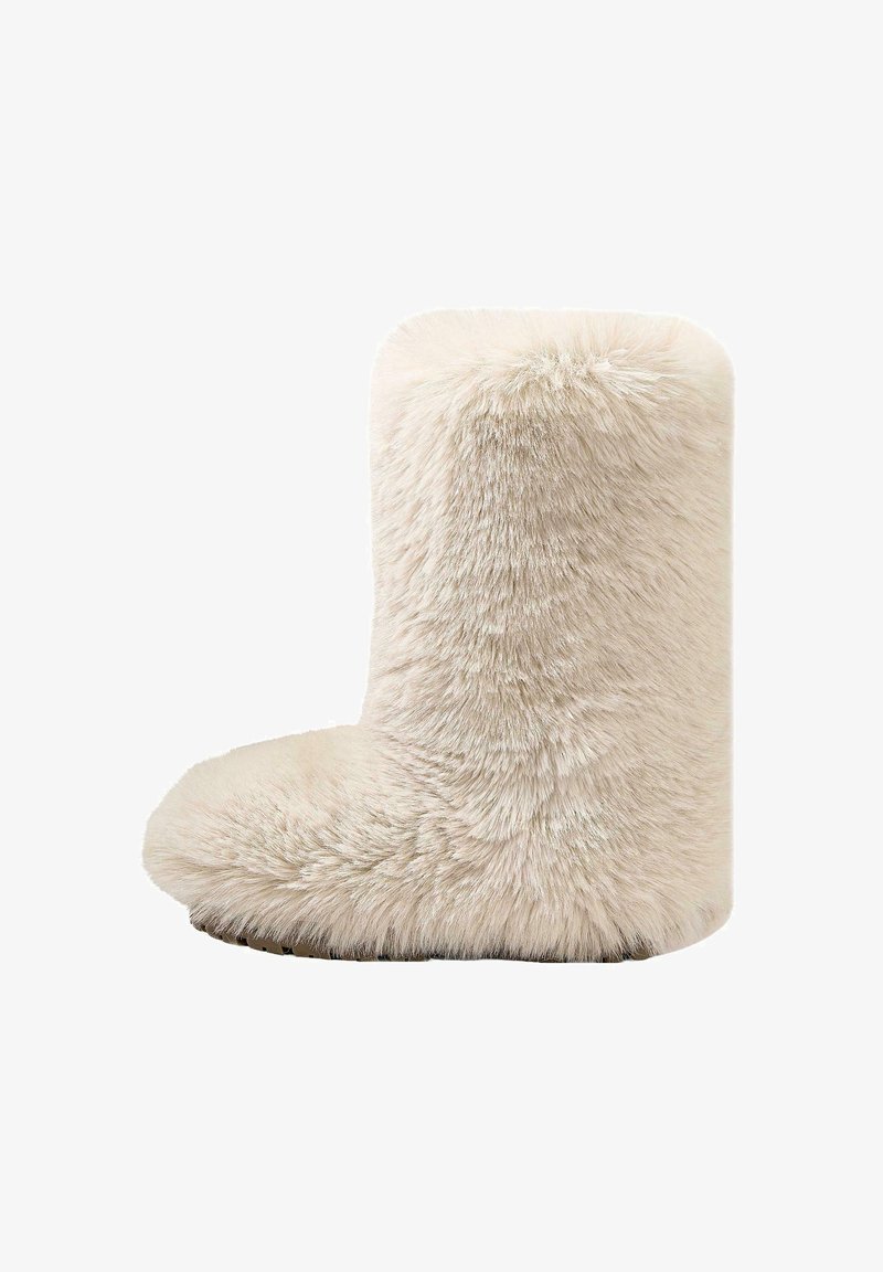 Fuskpälsstövel i krämfärg med rundad tå och fluffig textur. Kort höjd med en slät, slitstark sula för grepp.