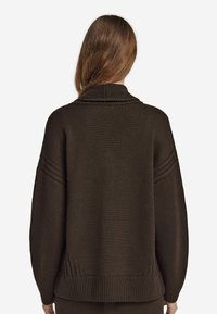 Överdimensionerad brun stickad tröja med sjalkrage, ribbade muddar och strukturerade mönster på axlarna och nederkanten. Mjuk, tjock material.