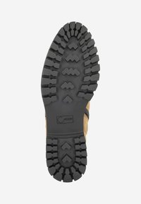 Black rubber boot sole with deep treads and zigzag patterns, light brown upper partially visible, logo embossed near the center.