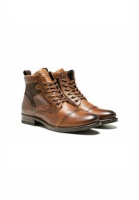 Bottines en cuir marron avec des panneaux en tissu texturé, bouts ronds, lacets et couture décorative ; dotées d'une languette à l'arrière.