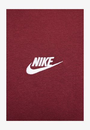 Camiseta de tejido burdeos con un logo de Nike bordado en blanco. Textura suave y diseño clásico de cuello redondo, sin patrones o acentos adicionales.