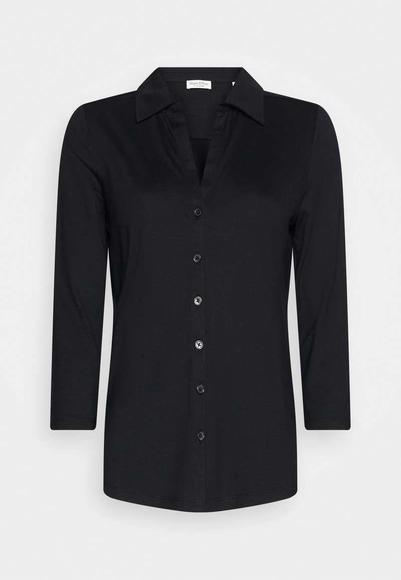 Chemise noire à manches longues avec col, sept boutons et une silhouette cintrée, présentée sur un fond clair uni.