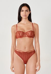Bordeaux kanten lingerieset met een balconette bh met golvende randen en bijpassende hoog-getailleerde slip met dubbele bandjes.