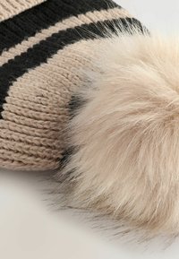 Cappello lavorato a maglia con strisce beige e nere, arricchito da un soffice e morbido pom-pom di pelliccia beige chiaro. La texture è dettagliata e corposa.