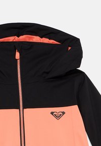 Czarna i koralowa kurtka z kapturem z zamkiem z przodu. Posiada kontrastujące panele, gładką teksturę oraz logo na lewej części klatki piersiowej.