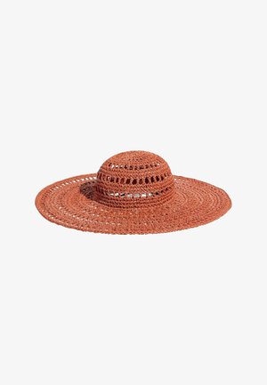 Plataus kraštelio, rūdžių spalvos nertinė saulės kepurė su apskritais raštais ir mažomis atviromis mezginio detalėmis aplink karūną.