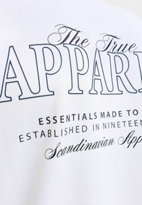 Κείμενο σε λευκό ύφασμα που γράφει The True Apparel Essentials made to last Established in nineteen fifty Scandinavian Apparel.