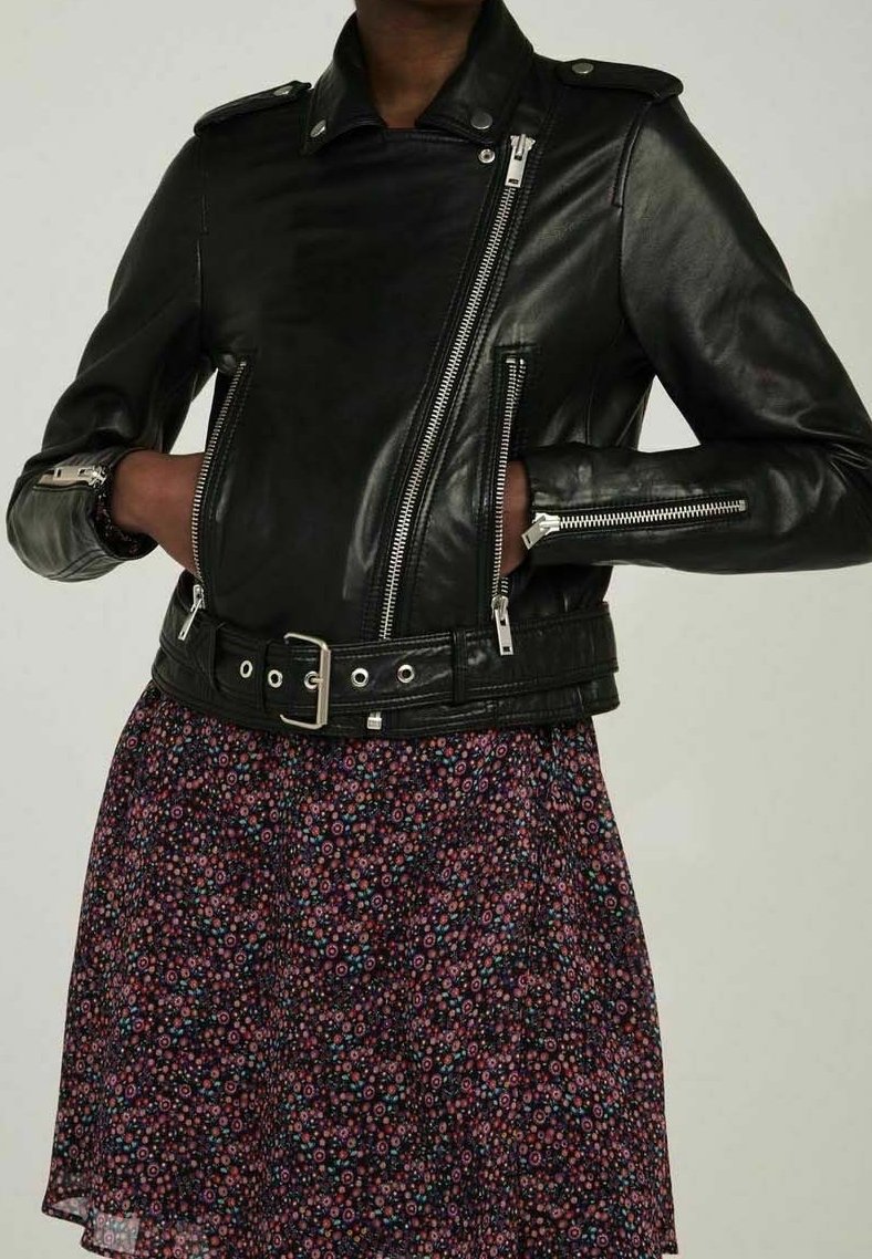 Svart läderbikerjacka med dragkedjor, axelremmar och bälte i midjan, kombinerad med en blommönstrad klänning i mörka färger.