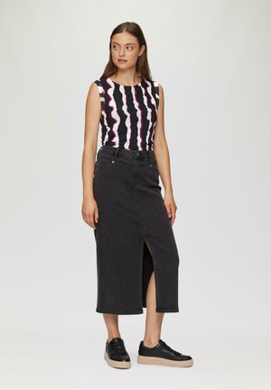 Haut sans manches noir avec des rayures ondulées blanches et roses, associé à une jupe en denim noir avec une fente à l'avant et des baskets noires avec une semelle beige.