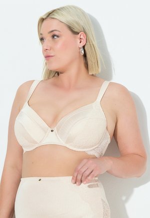 Beige kant bh met verticale ribbels, onderwire ondersteuning en decoratieve knoop aan de voorkant. Dikke, verstelbare bandjes voor comfort.