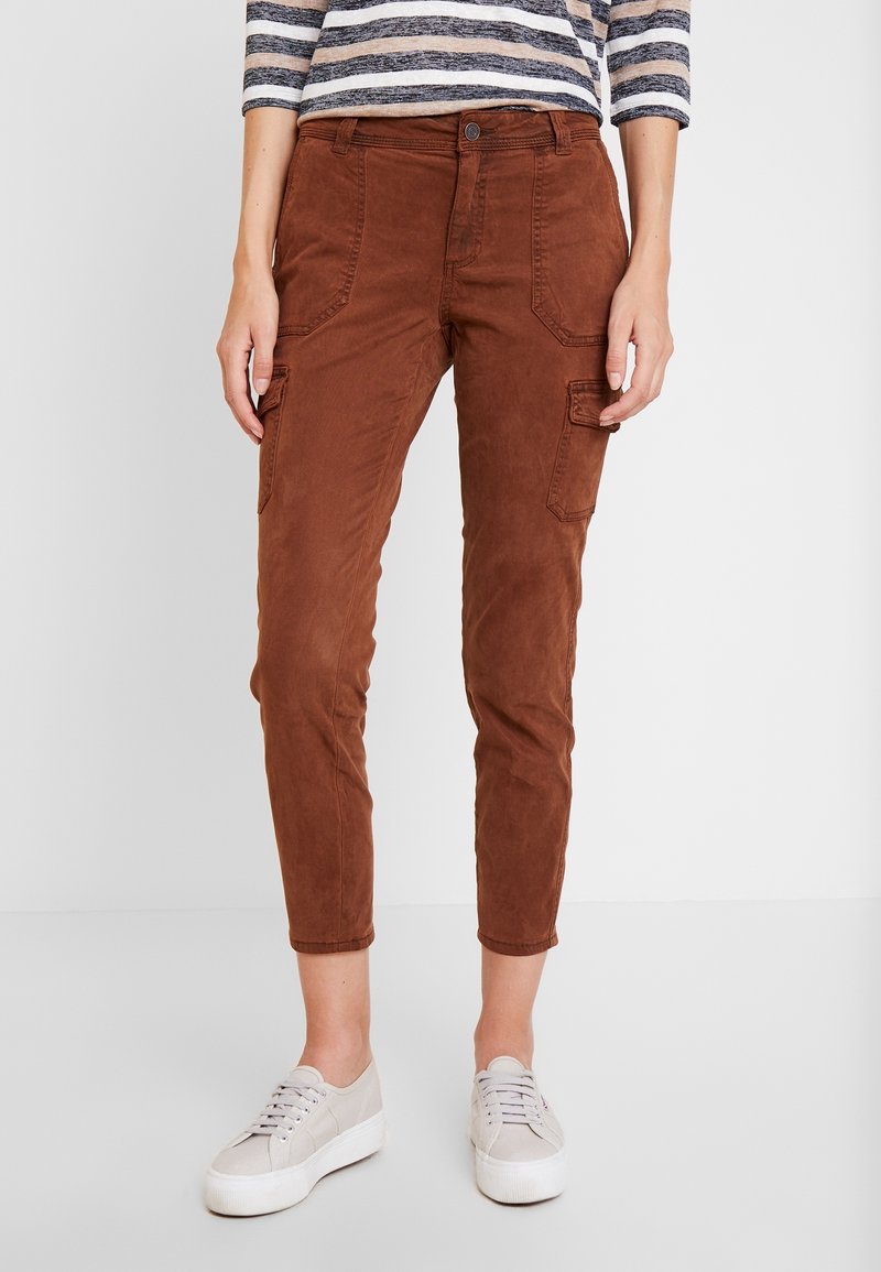 Brown cargo pants with a slim fit, crafted from soft fabric. Features front pockets and a rolled hem, paired with light-colored sneakers.
