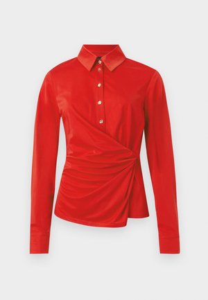 Κόκκινη μακρυμάνικη μπλούζα με κλασικό γιακά, χρυσά κουμπιά στο μπροστινό μέρος και λεπτομέρεια με σούρες σε μία πλευρά στη μέση.