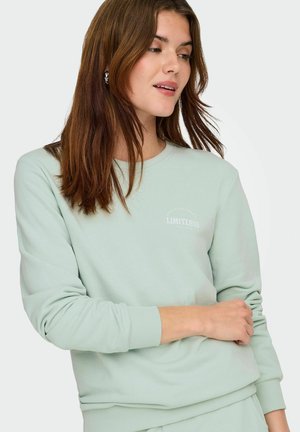 Sweatshirt vert clair en tissu doux, doté d'un col rond, de poignets côtelés et d'un petit logo "LIMITLESS" sur le devant.