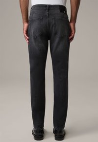 Jeans de mezclilla negra con un diseño de pierna recta, dos bolsillos traseros y un acabado texturizado. Se aprecia una costura reforzada y una cinturilla suave.