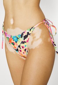 Fundo de bikini floral com um padrão colorido em rosa, laranja e preto, com nós laterais e um design de cintura baixa. Tecido macio e elástico.