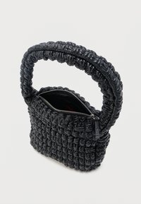 Μαύρη τσάντα με ραφές, με χοντρή στρογγυλεμένη λαβή και ασημένιο φερμουάρ που είναι μερικώς ανοιχτό, αποκαλύπτοντας τον εσωτερικό χώρο.